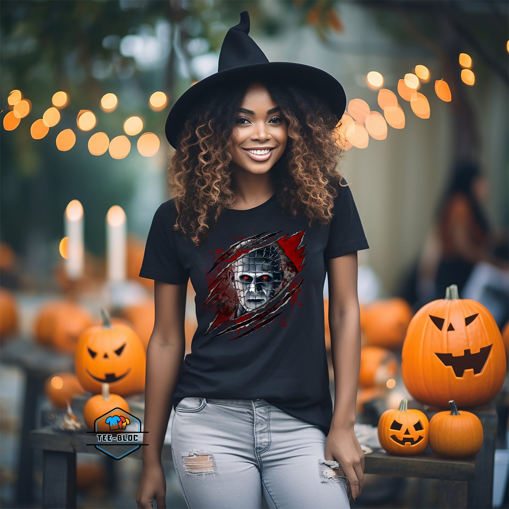 Woman wearing a black t-shirt with a pinhead hellraiser graphic design, standing in front of pumpkins and blurred lights