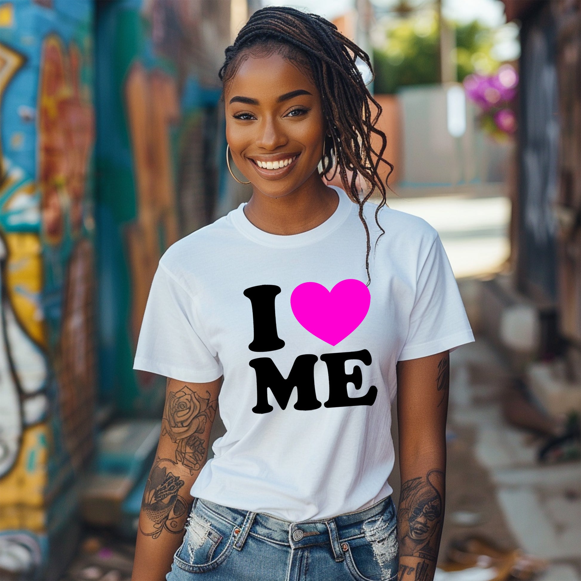 Woman wearing a white t-shirt with 'I ❤️ ME' design, standing in front of a colorful mural.