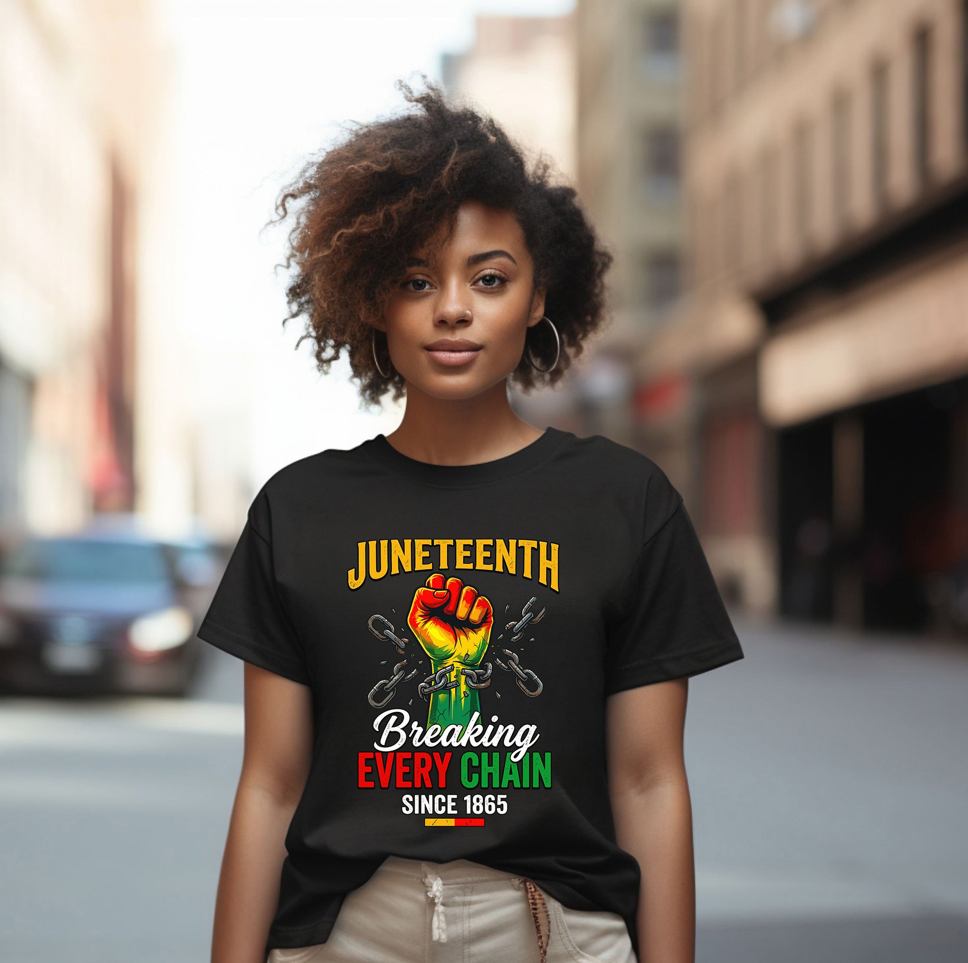 Person wearing a black t-shirt with Juneteenth design on a city street.