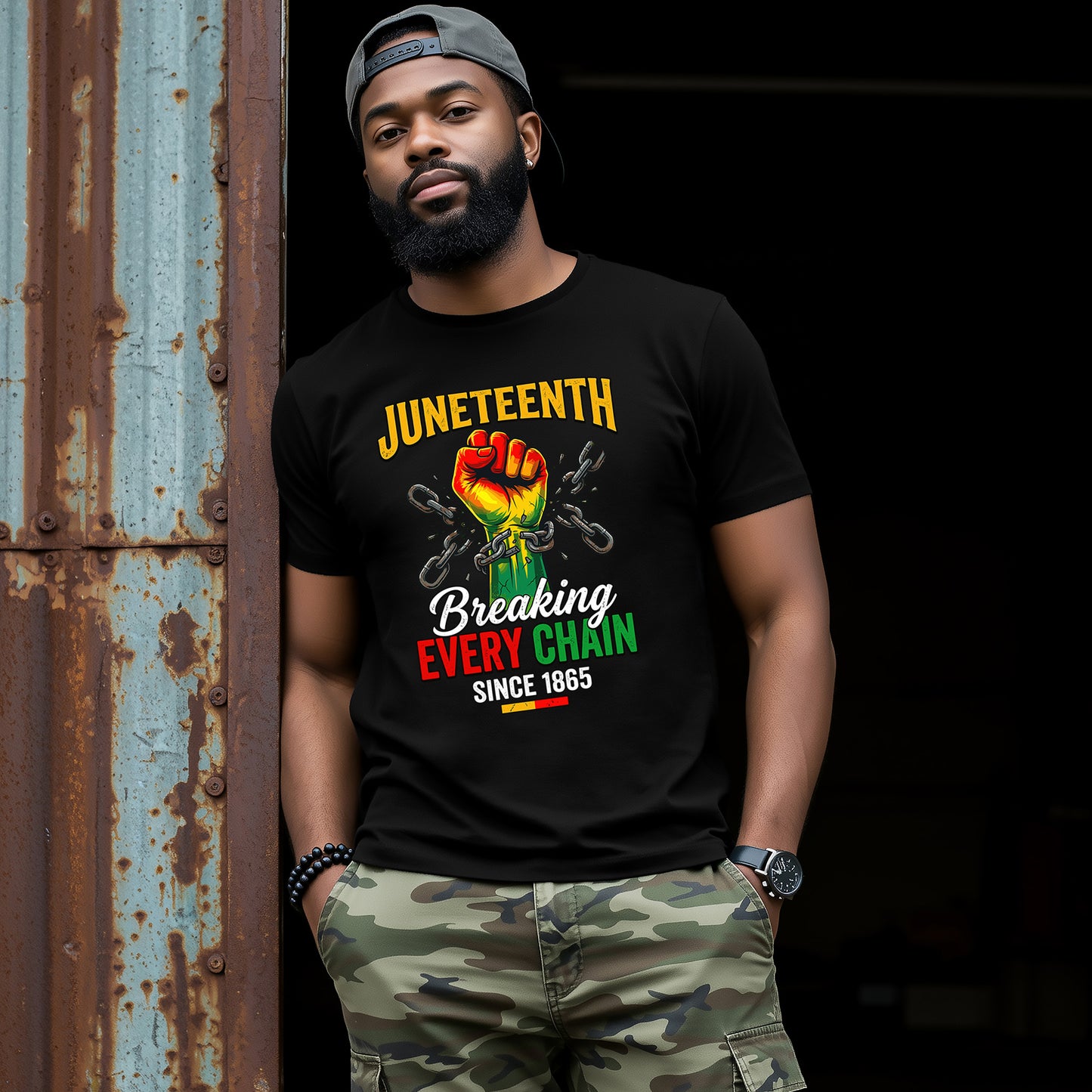Man wearing a black t-shirt with Juneteenth design, standing against a dark background.