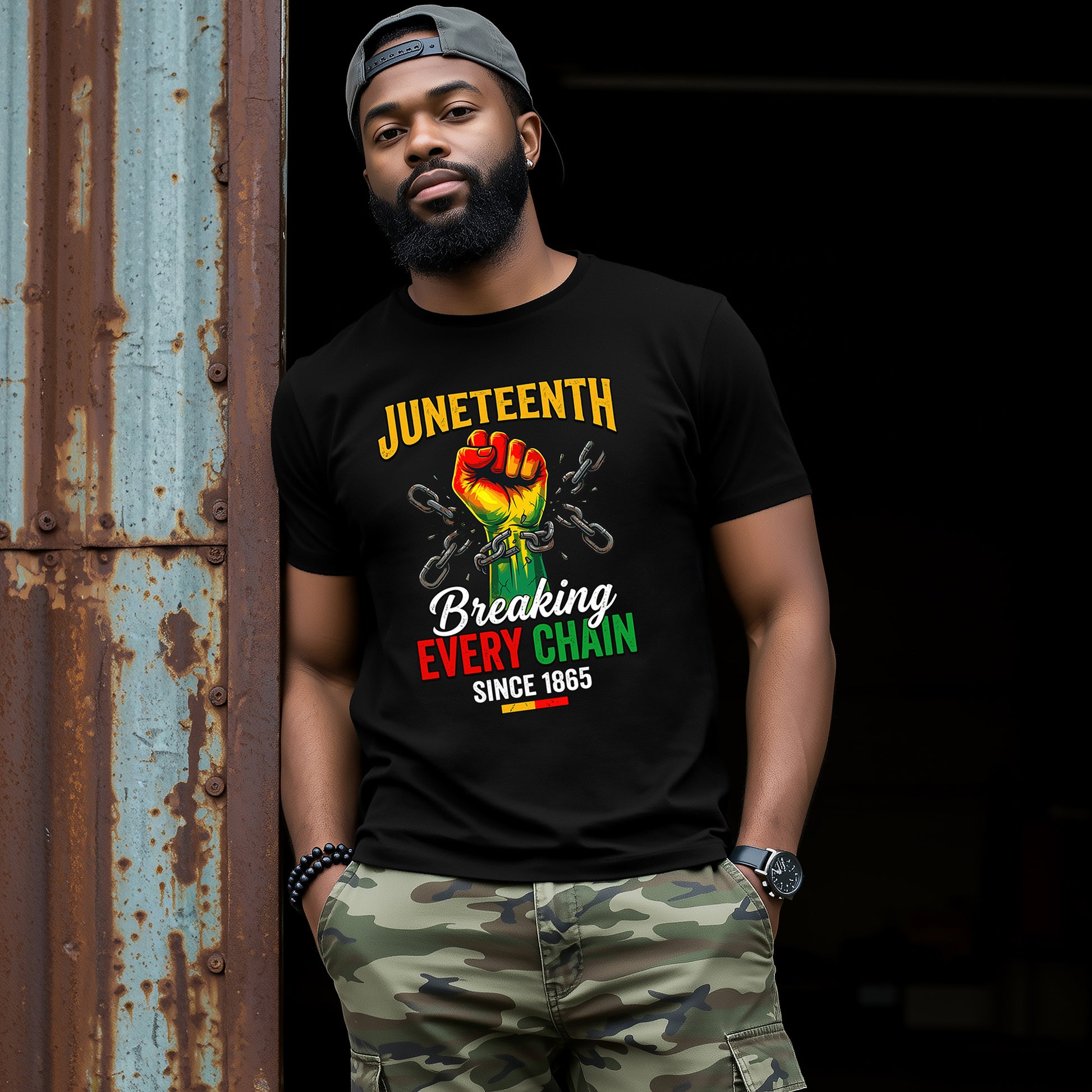 Man wearing a black t-shirt with Juneteenth design, standing against a dark background.